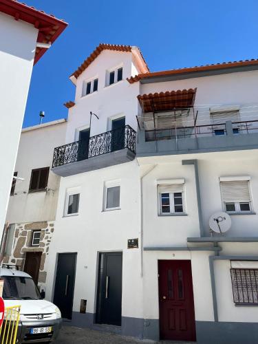 a white building with a red door and a balcony at H I Alojamento in Manteigas