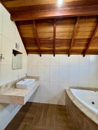 a bathroom with a sink and a bath tub at Pousada Vista do Paraíso in Monte Verde