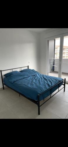 Ce lit se trouve dans une chambre blanche dotée d'une couette bleue. dans l'établissement Appartement Cap d'Agde, au Cap d'Agde