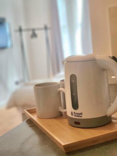 two cups sitting on a cutting board with a coffee pot at London En-suite Double Rooms - Leytonstone E11 in London