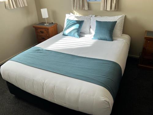 a bedroom with a large bed with blue pillows at Airport Christchurch Motel in Christchurch