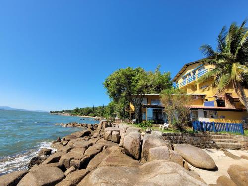 uma casa na costa de uma praia rochosa em Prainha da Nina Apartamentos em Florianópolis