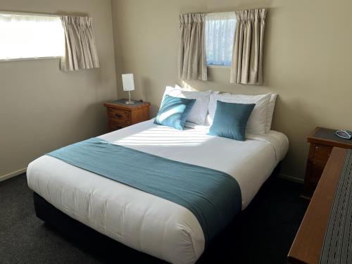 a bedroom with a large bed with blue pillows at Airport Christchurch Motel in Christchurch