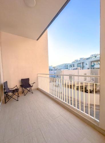 a balcony with two chairs and a large window at Lovely room ensuite in Swieqi in Is-Swieqi