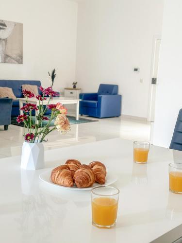 a table with a plate of pastries and two glasses of orange juice at Lovely room ensuite in Swieqi in Is-Swieqi