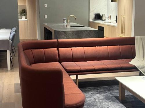 a brown couch in a living room with a kitchen at Luxurious Family Retreat in Blackburn