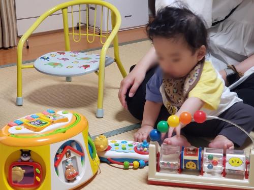 a baby sitting on the floor playing with toys at Business Ryokan Akashiya Annex in Akashi