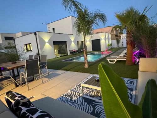 une cour arrière avec une piscine et une maison dans l'établissement Villa Vanille Cap d Agde Luxe piscine chauffée 5 étoiles, au Grau-dʼAgde