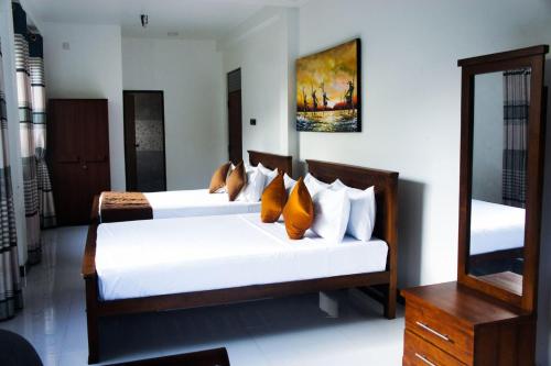 a bedroom with two beds and a mirror at Ark Cabin Villa in Kandy