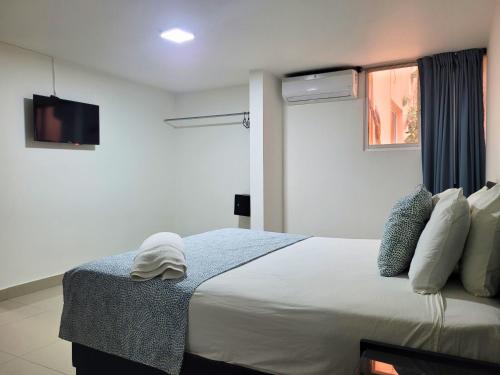 a bedroom with a bed with a tv on the wall at Hotel Olimpo in La Romana
