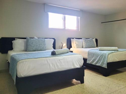 a bedroom with two beds and a window at Hotel Olimpo in La Romana