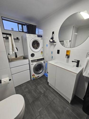 a bathroom with a washing machine and a sink at Central 2 Beddy on Beach Road! in Batemans Bay