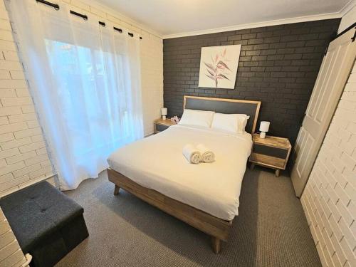 a bedroom with a bed with white sheets and a window at Central 2 Beddy on Beach Road! in Batemans Bay