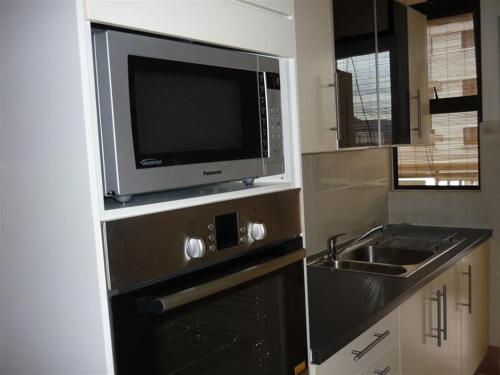 a kitchen with a sink and a tv on a wall at SS GREY HOMESTAY Pelangi Utama in Petaling Jaya