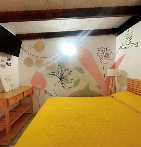 a bedroom with a yellow bed and flowers painted on the wall at Dona Monica in Ituzaingó