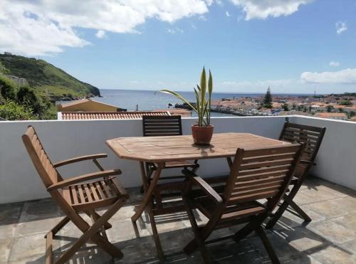 a wooden table and chairs on a balcony with a potted plant at Casa Monte Queimado in Horta