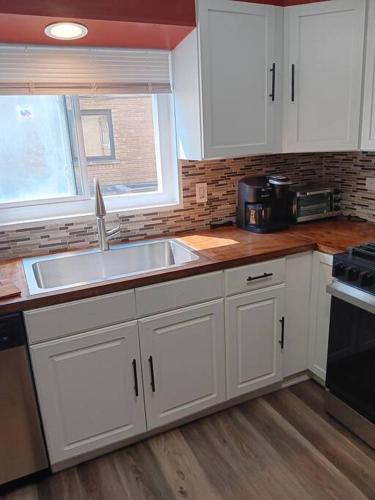 a kitchen with white cabinets and a sink and a window at Condo Apartment Near Midway Airport in Chicago