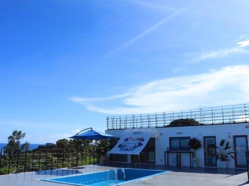 a building with a swimming pool in front of it at GLORY ISLAND OKINAWA Yabusachi Resort in Nanjo