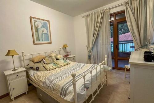 ein Schlafzimmer mit einem weißen Bett und einem Balkon in der Unterkunft Beautiful and quiet family villa in Kableshkovo