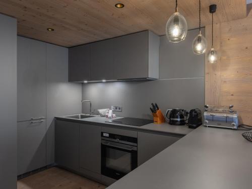 una cucina con armadi grigi e piano di lavoro di Magnifique appt au cœur de Courchevel avec accès bien-être - FR-1-562-81 a Courchevel