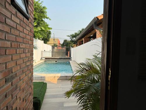 a swimming pool next to a house with a brick wall at Casa Privada con Piscina y Parking Gratis en Asunción in Asunción