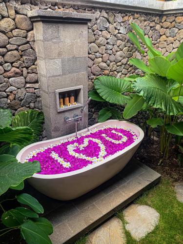 a bath tub covered in flowers in a garden at Sumberkima Resort in Pemuteran