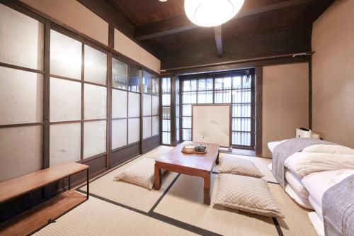 a room with a bed and a table and windows at 吉祥庵 in Nishinotōindōri