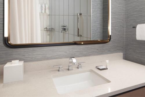 a bathroom with a sink and a large mirror at Houston Marriott Sugar Land in Sugar Land