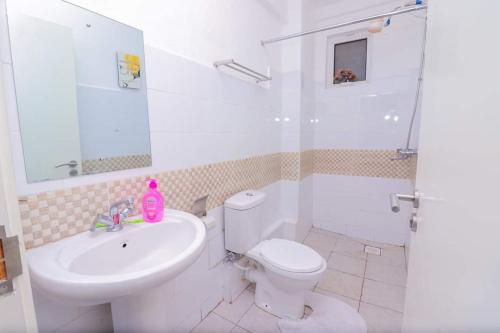a bathroom with a white toilet and a sink at The Gem-3 Bedroom Kiambu Road-Best Rated in Nairobi