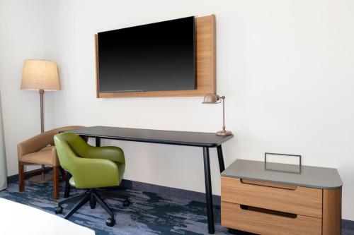 a desk with a chair and a television on a wall at Fairfield by Marriott Inn & Suites Sioux Center in Sioux Center