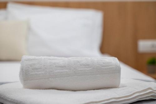 a stack of white towels on a bed at sunny rock 2 apartments in Lagoúdi Zía