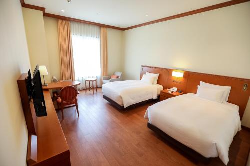 a hotel room with two beds and a television at GrandEmpireHotel in Onojo