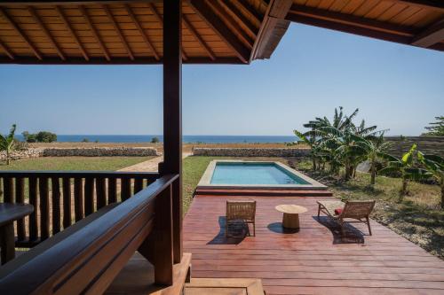 a deck with a swimming pool with chairs and a table at Anna Villas by Sumba-Beach in Memboro