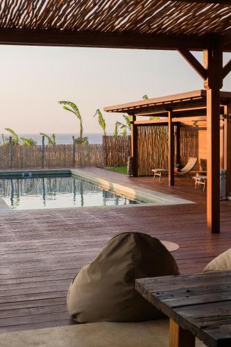 a swimming pool with a table and a wooden deck at Anna Villas by Sumba-Beach in Memboro