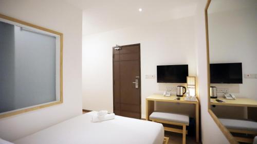 a room with a bed and a desk and a mirror at Vivids Hotel in Kuala Lumpur