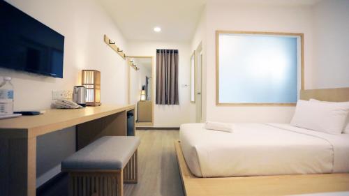 a room with two beds and a desk with a television at Vivids Hotel in Kuala Lumpur