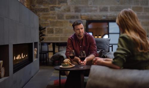 a man and woman sitting around a table in a room with a fireplace at RACV Hobart Hotel in Hobart