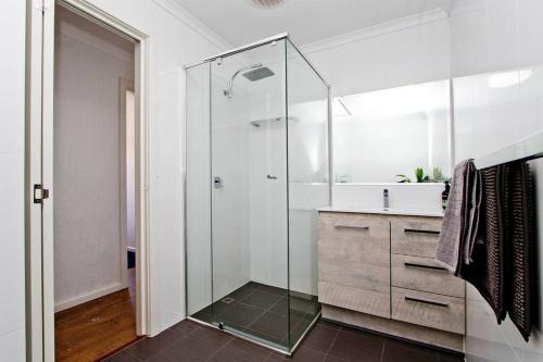 グレネルグにあるGetaway on Gordon - Comfortable stylish apartmentのガラスのシャワーと洗面台を備えたバスルーム