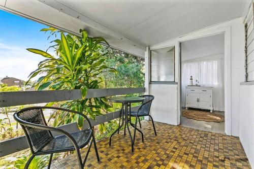 Un balcón con mesa y sillas y una cocina. en Sandown Beachside Cottage, en Bongaree