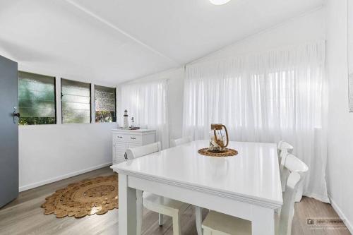 Un comedor blanco con una mesa y sillas blancas. en Sandown Beachside Cottage, en Bongaree