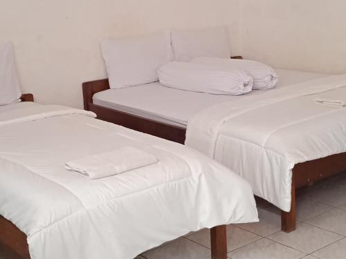 a room with two beds with white sheets and pillows at Hotel Wisata in Labuan Bajo