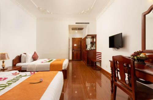 a hotel room with two beds and a television at YASODHARAPURA Residence in Siem Reap