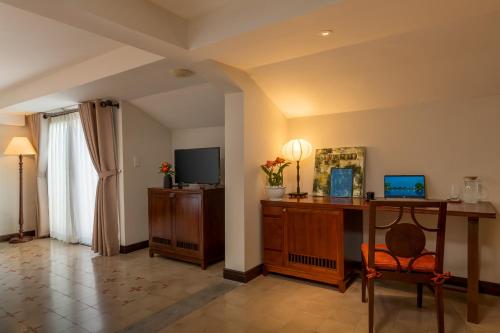 a living room with a desk and a television at RiverTown Hoi An Resort & Spa in Hoi An