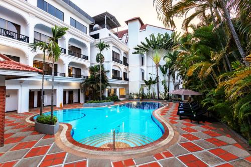 a swimming pool in front of a building with palm trees at YASODHARAPURA Residence in Siem Reap
