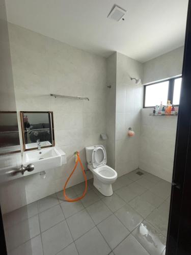 a bathroom with a toilet and a sink with an orange hose at Saujana Perdana Homestay in Sungai Buluh