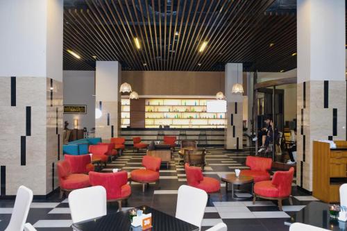 a lobby of a restaurant with red chairs and tables at The Luxton Cirebon Hotel and Convention in Cirebon