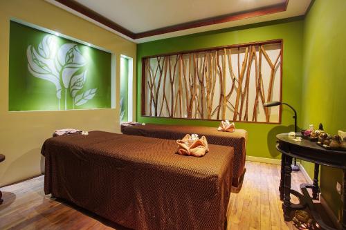 two beds in a room with green walls at YASODHARAPURA Residence in Siem Reap