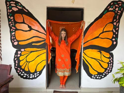 a woman in an orange dress with butterfly wings at 20 House Arugam in Arugam Bay