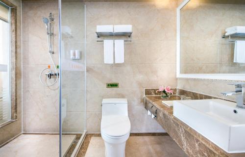 a bathroom with a toilet and a sink and a shower at Vienna International Hotel Jieyang Yangmei Jade hotel in Jieyang