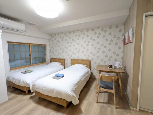 two beds in a room with a table and a desk at Nikko Beans Hotel in Nikko
